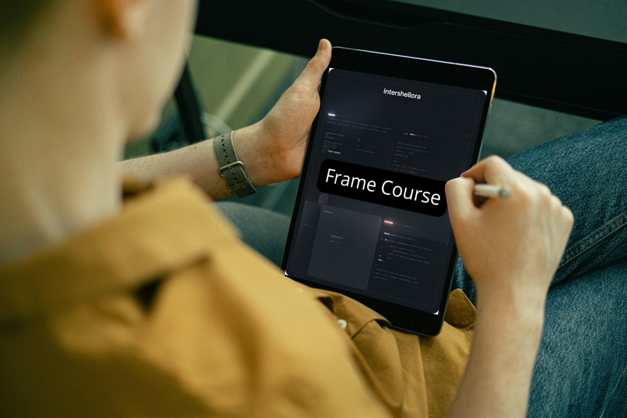Person holding a tablet with 'Frame Course' displayed on the screen, wearing a yellow jacket.